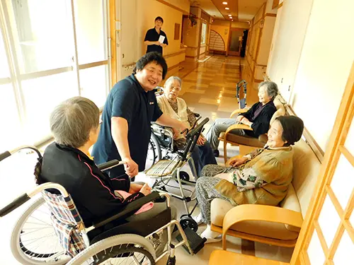 ▲施設廊下での楽しそうな団らん。皆さん笑顔いっぱいですね！